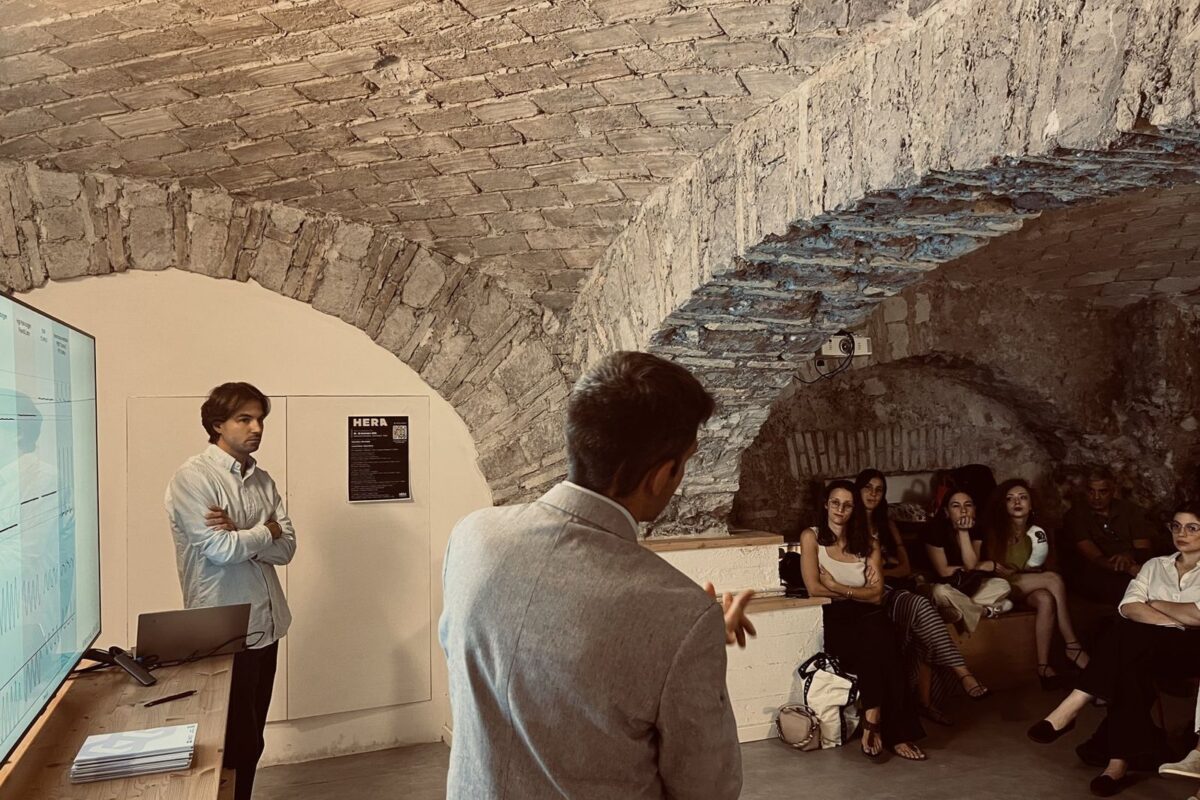 Un gruppo ascolta un relatore in una sala con volte in pietra